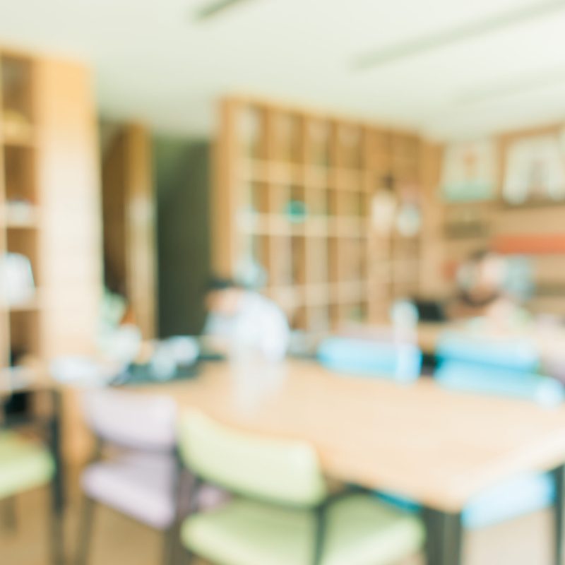 School classroom in blur background without young student; Blurry view of elementary class room no kid or teacher with chairs and tables in campus. Vintage effect style pictures.
